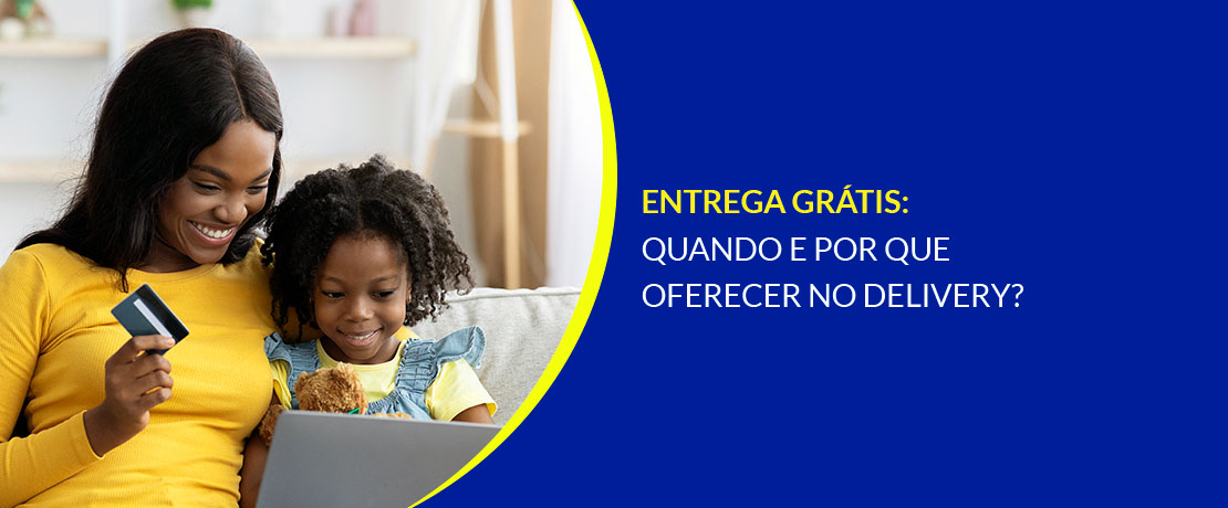 Mãe e filha pequena juntas no sofá, sorrindo, com o notebook aberto. A mãe com o cartão de crédito em uma das mãos